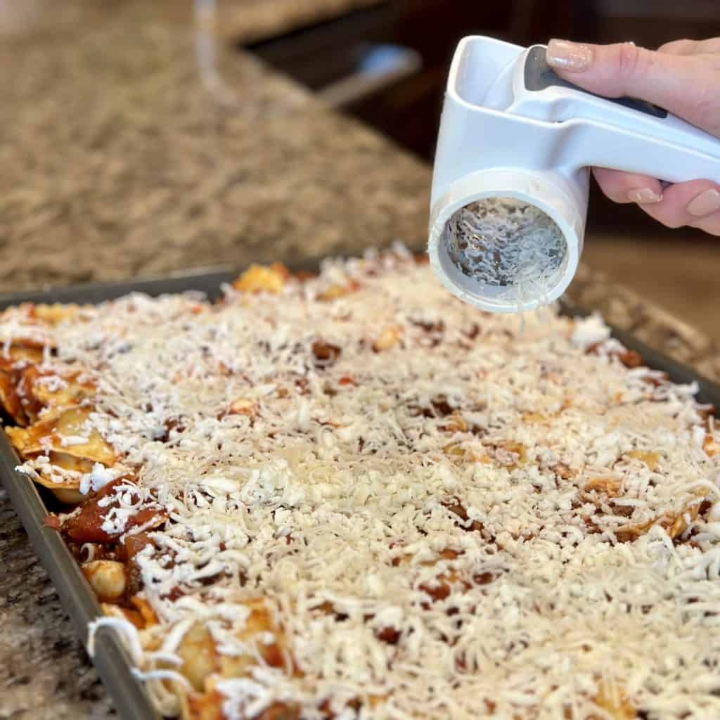 Shredding parmesan and mozzarella on ravioli.