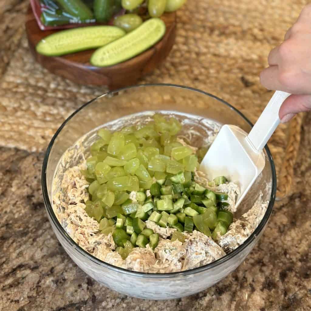 A bowl containing ingredients to make a cucumber chicken salad.