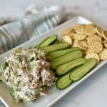 A plate of chicken salad, cucumbers and crackers.