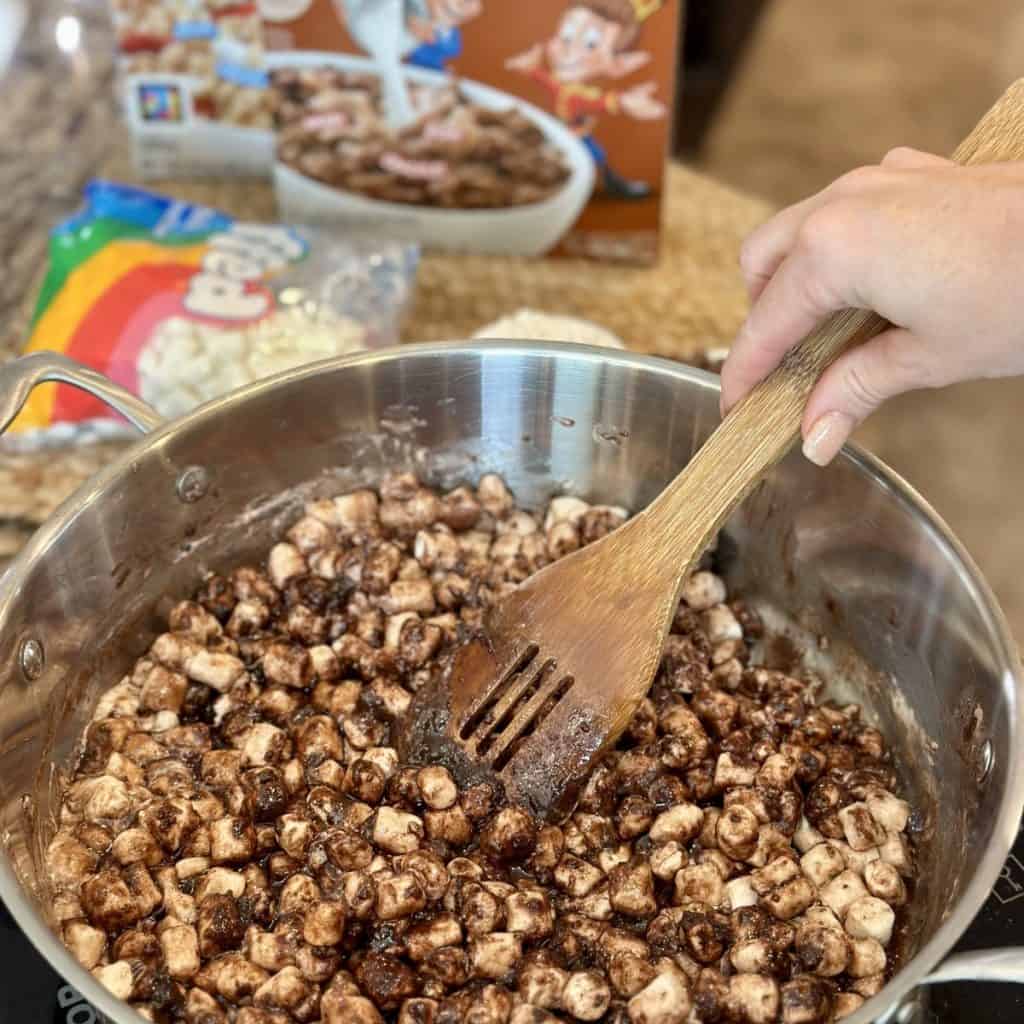 Mixing in marshmallows into chocolate in a skillet.