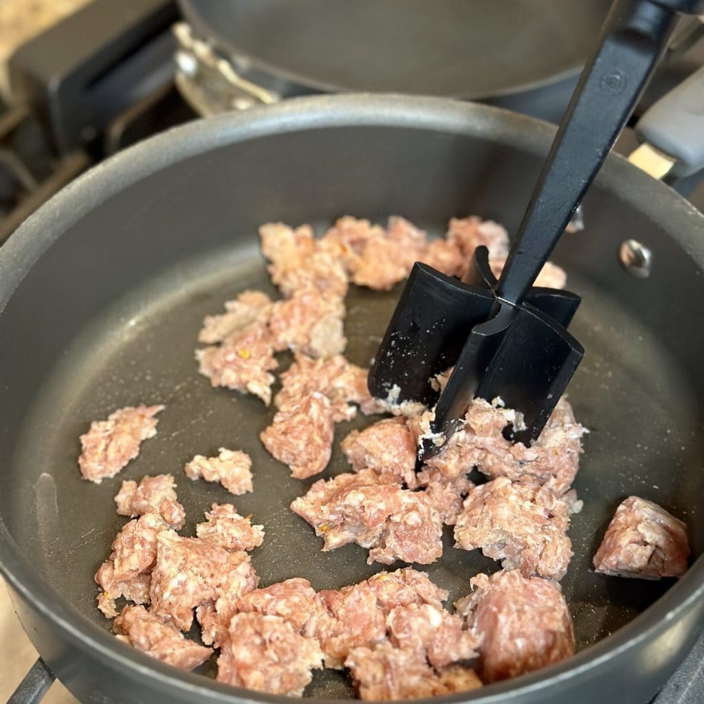 Crumbling sausage in a pan.