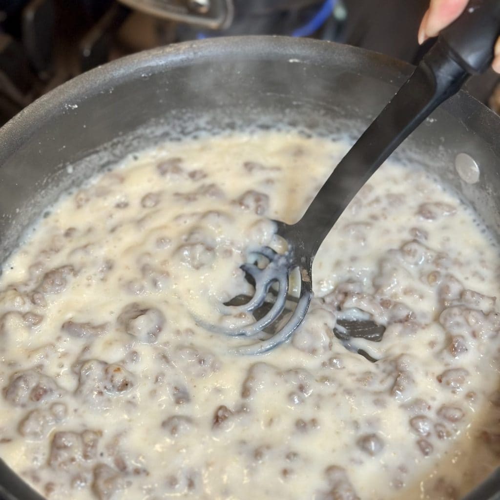 Stirring milk into breakfast gravy.