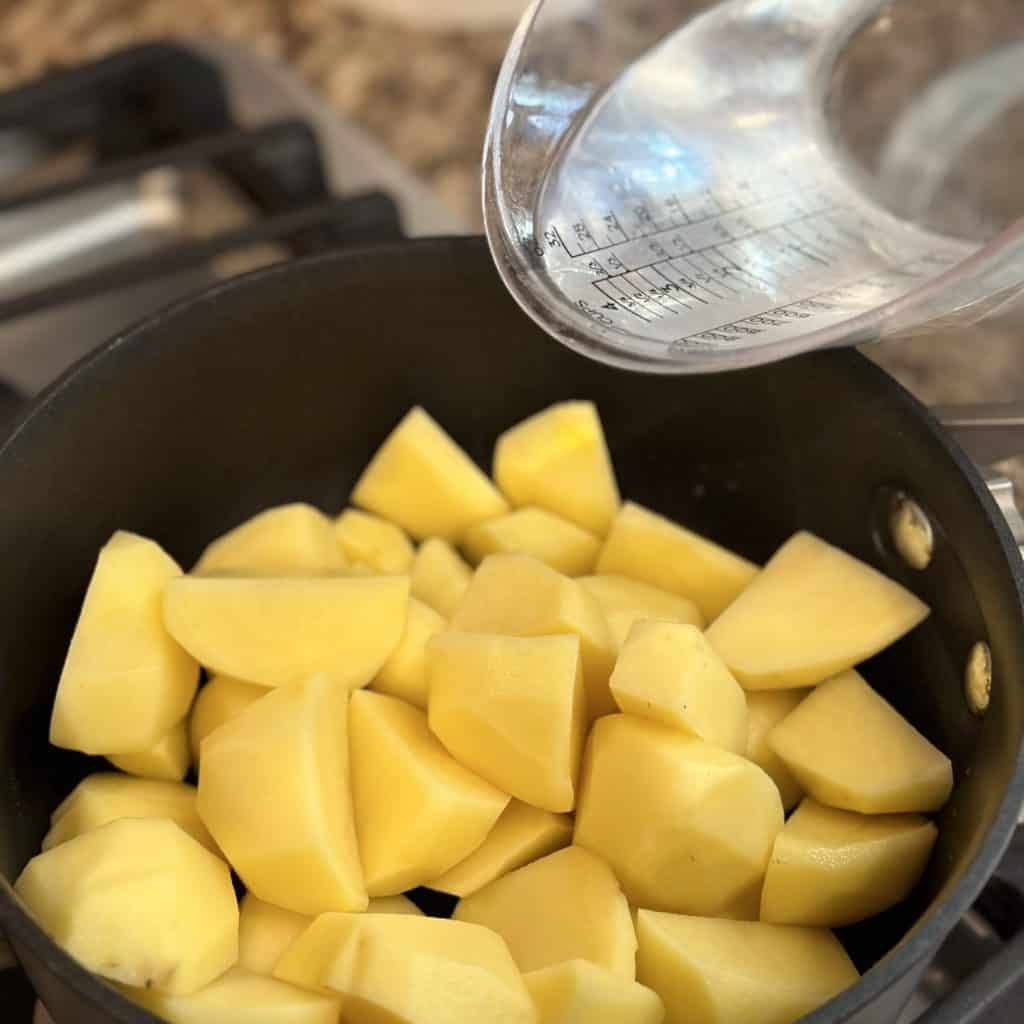 Adding water to potatoes in a saucepan.