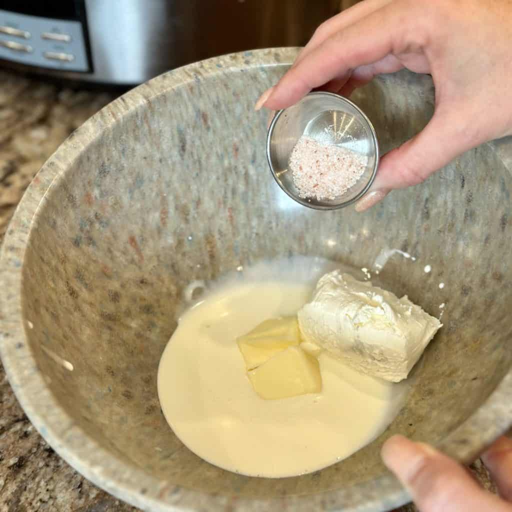 Adding salt to a bowl of cream and butter.