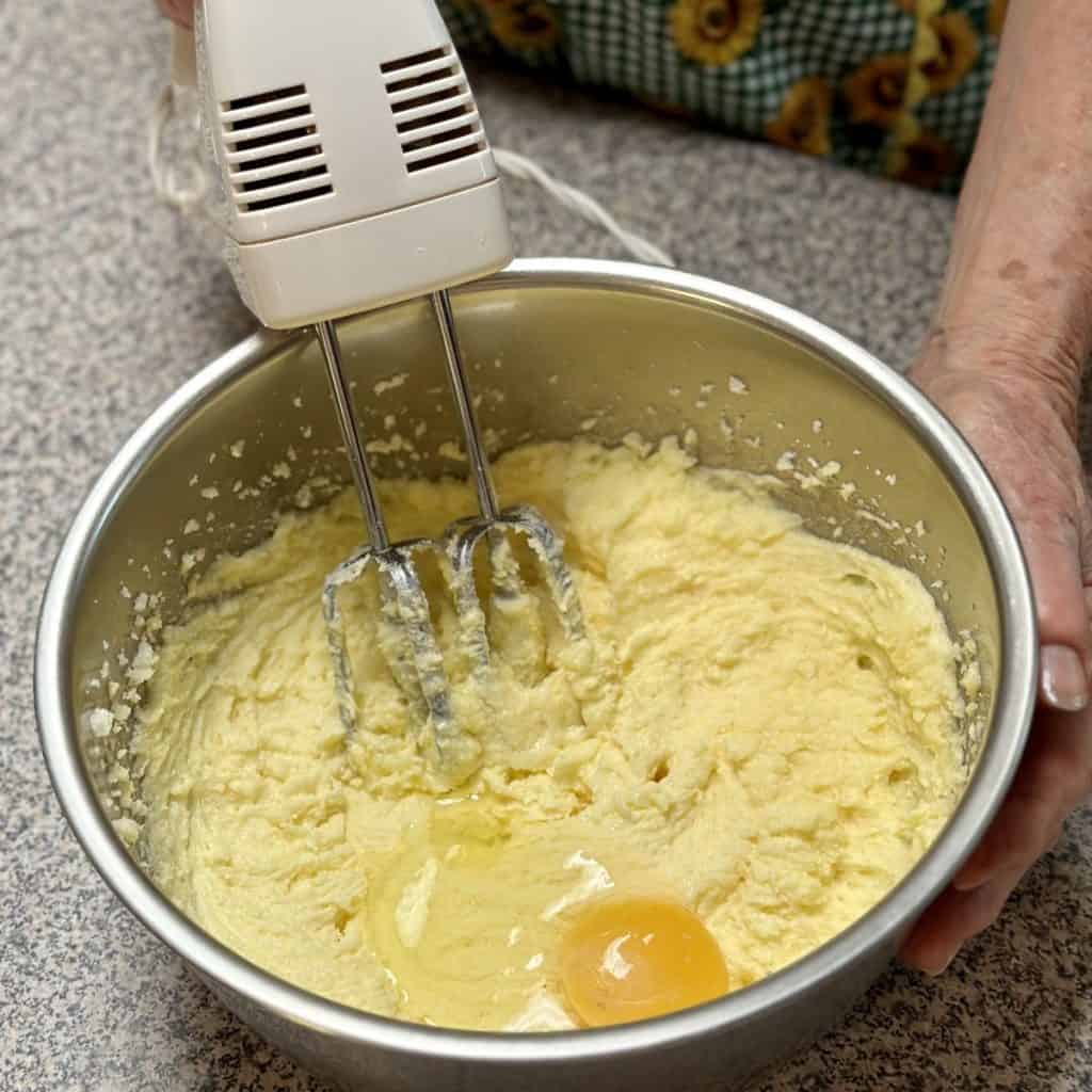 Adding eggs to batter in a bowl.