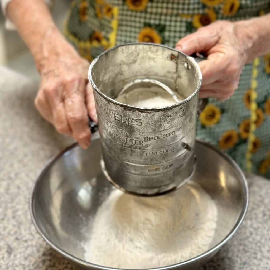 Sifting drying ingredients for a cake.