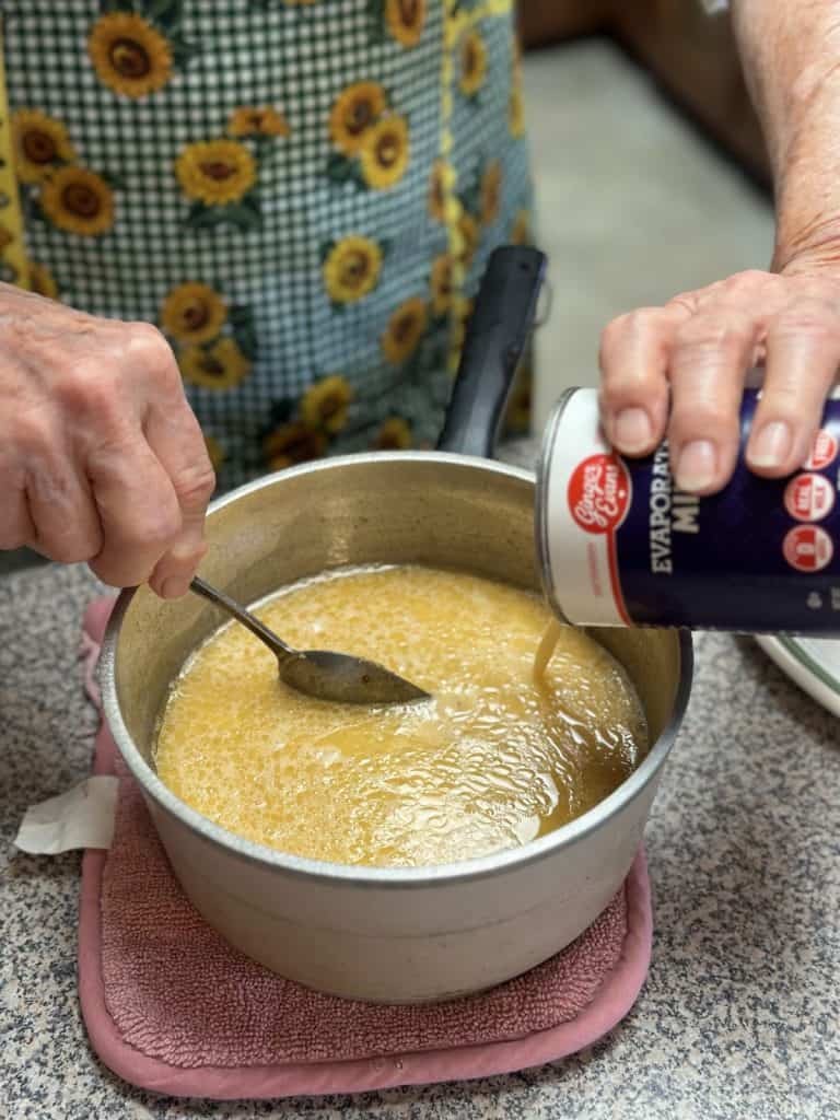 Mixing together butter, brown sugar and evaporated milk in a saucepan.