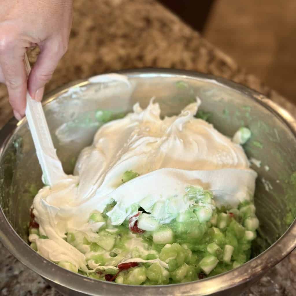 Folding whipped topping in a green fluff salad.