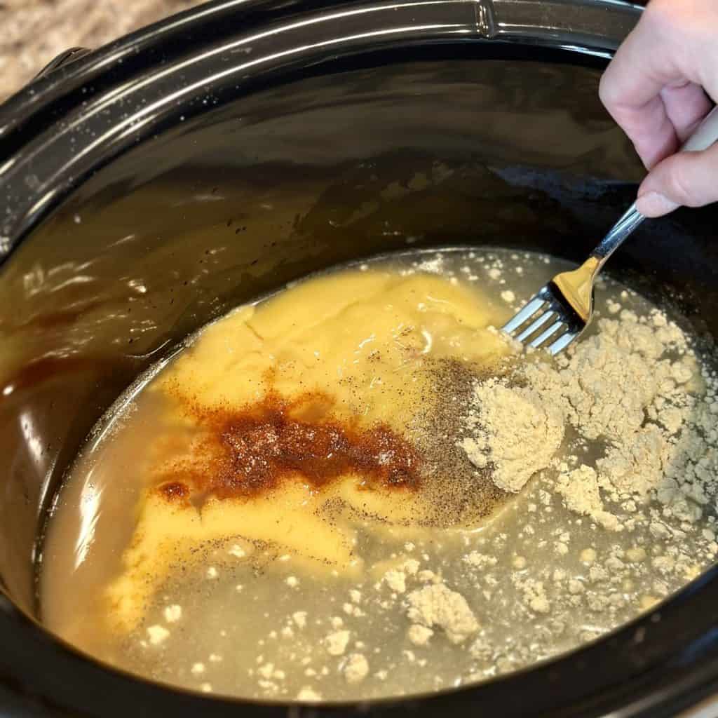 Mixing together ingredients for gravy in a crockpot.