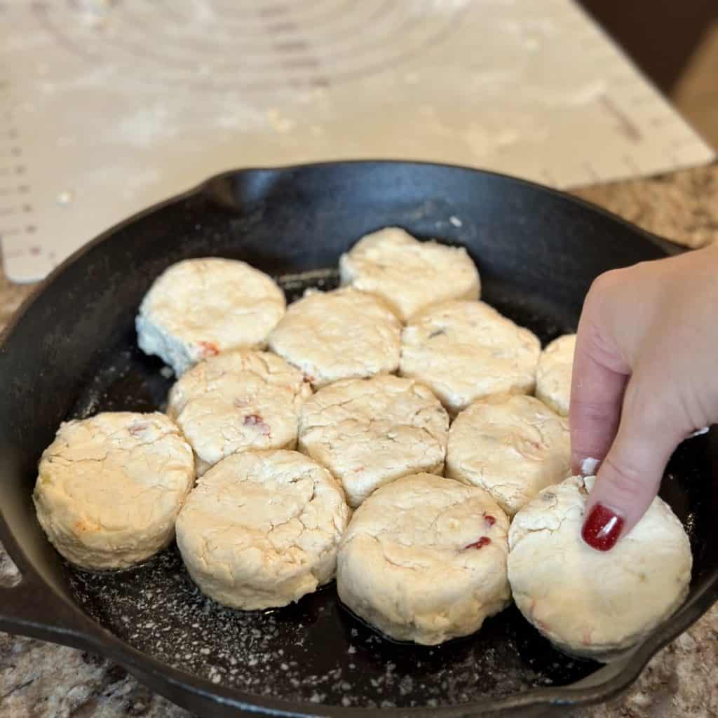 Laying biscuits in a cast iron skillet.