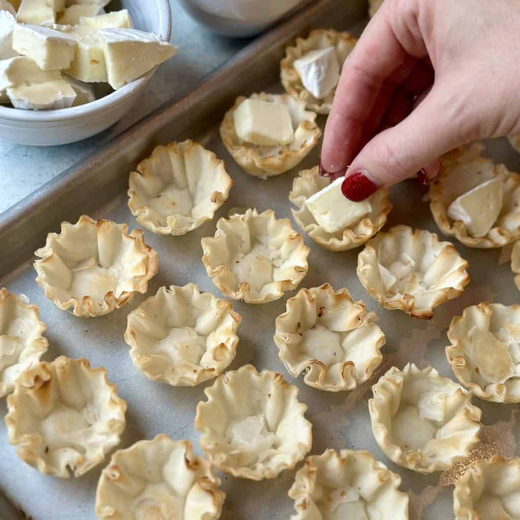 Adding brie to phyllo shells.