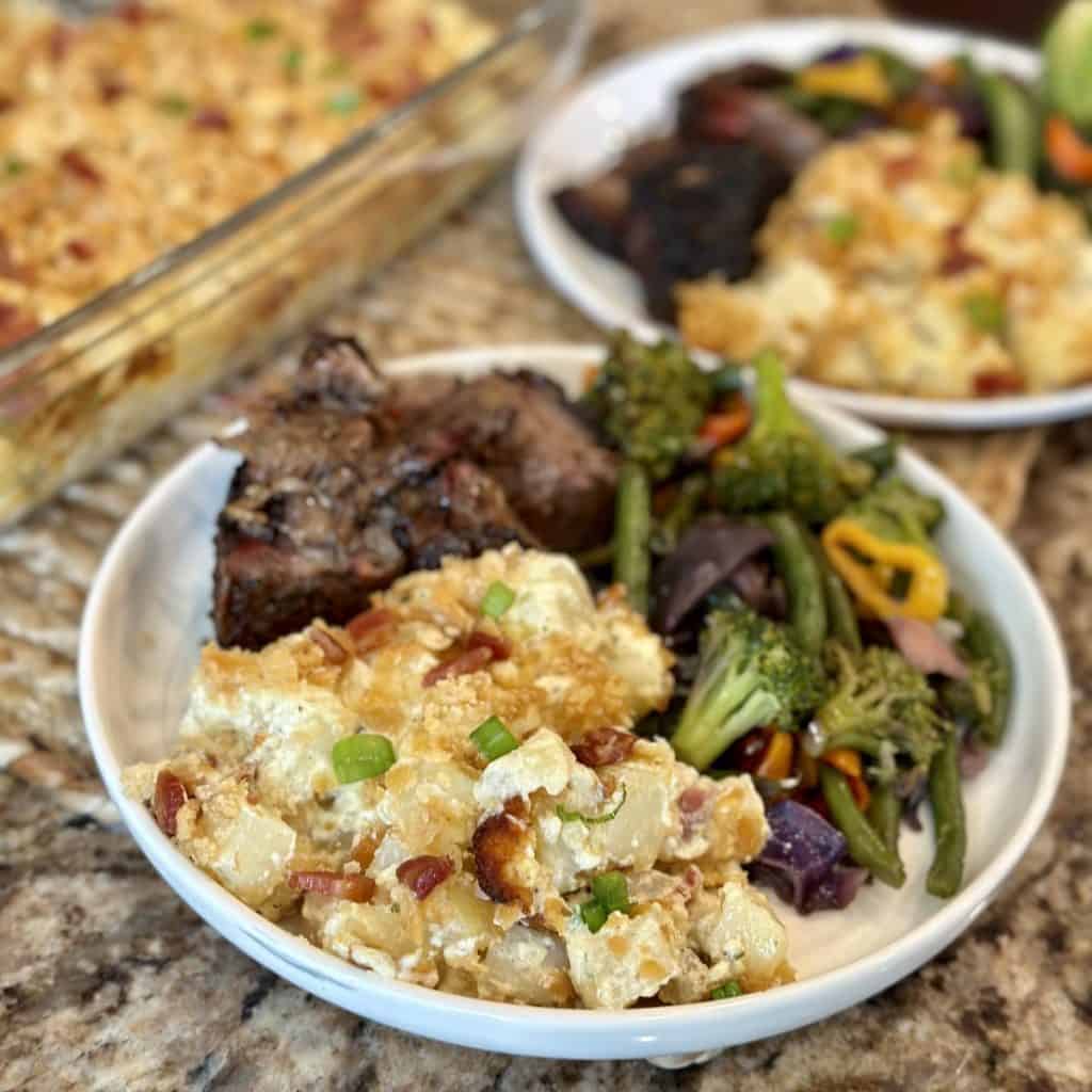 A finished plate of beef, vegetables and potatoes.