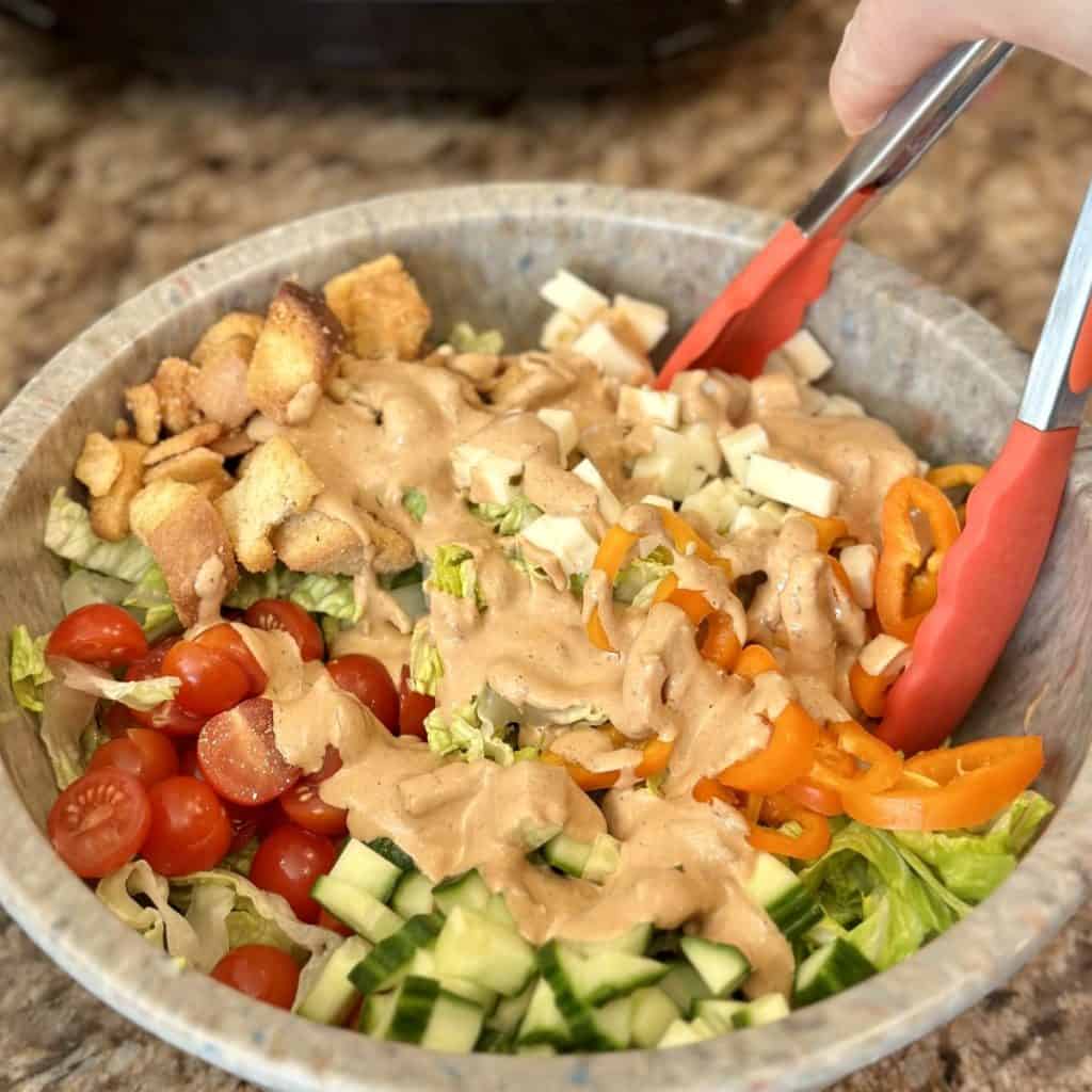 Mixing together the ingredients for a crispy chicken salad in a bowl.