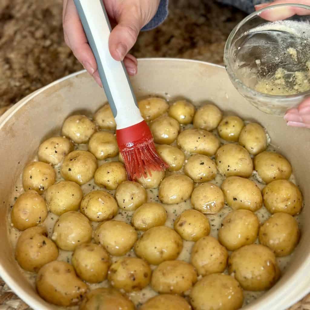Brushing garlic butter on potatoes.