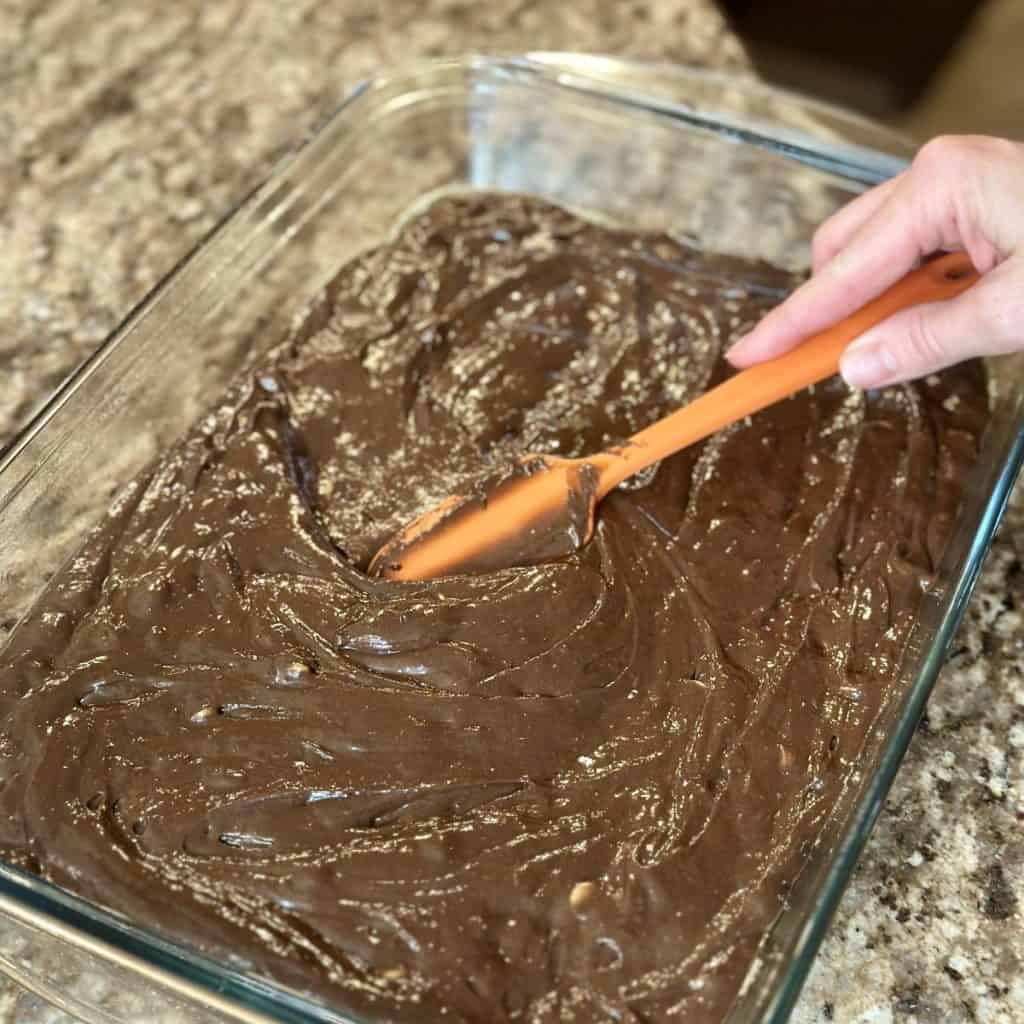 Spreading chocolate cake batter in a baking dish.