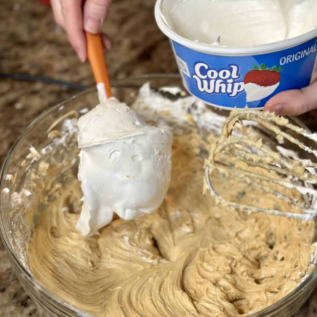 Adding cool whip to a frosting mixture.