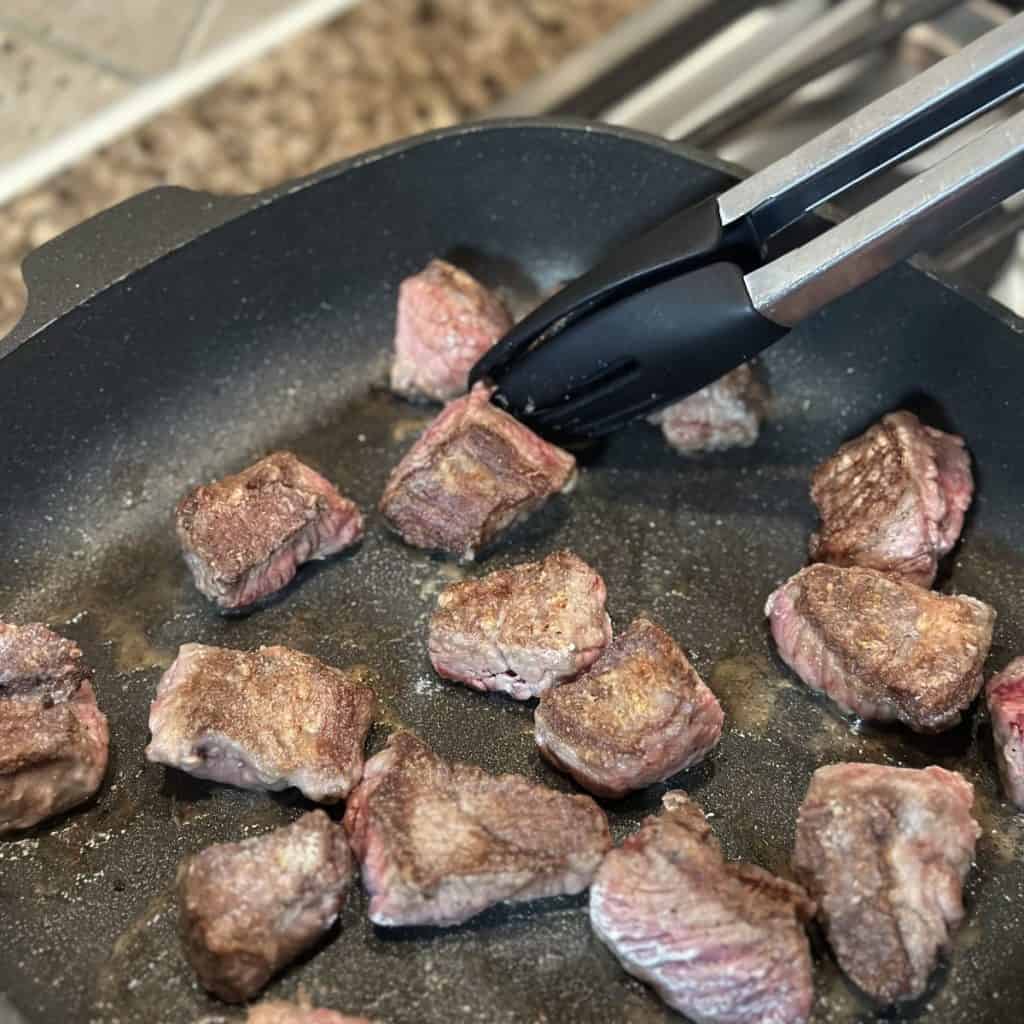 Searing a seasoned chuck roast in a skillet.