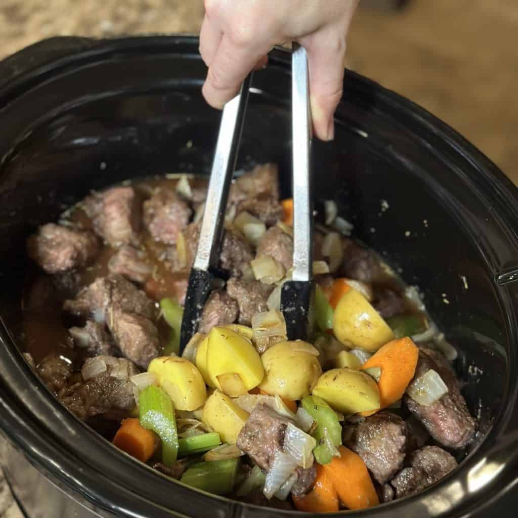 Mixing together beef stew in a crockpot.