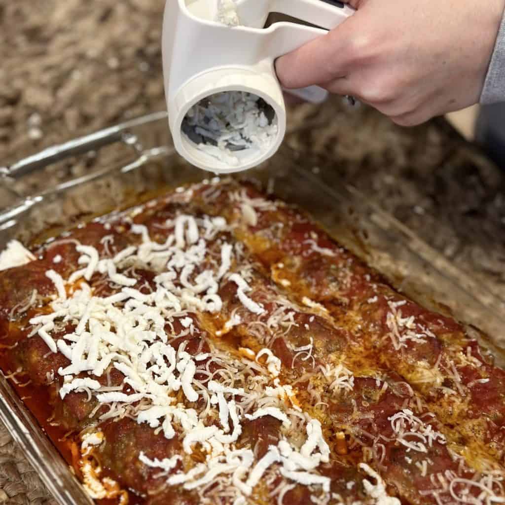 Adding cheese to the tops of meatballs.