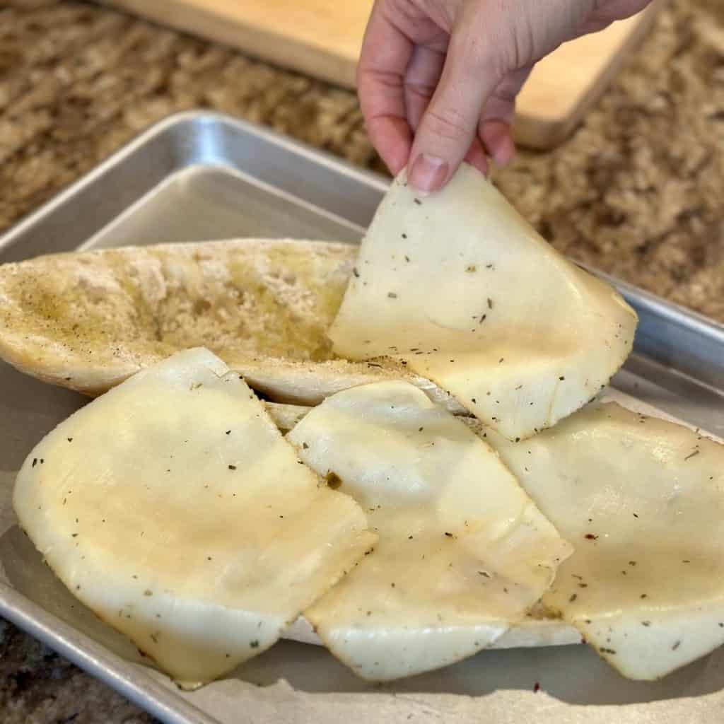 Adding cheese to a sub sandwich.