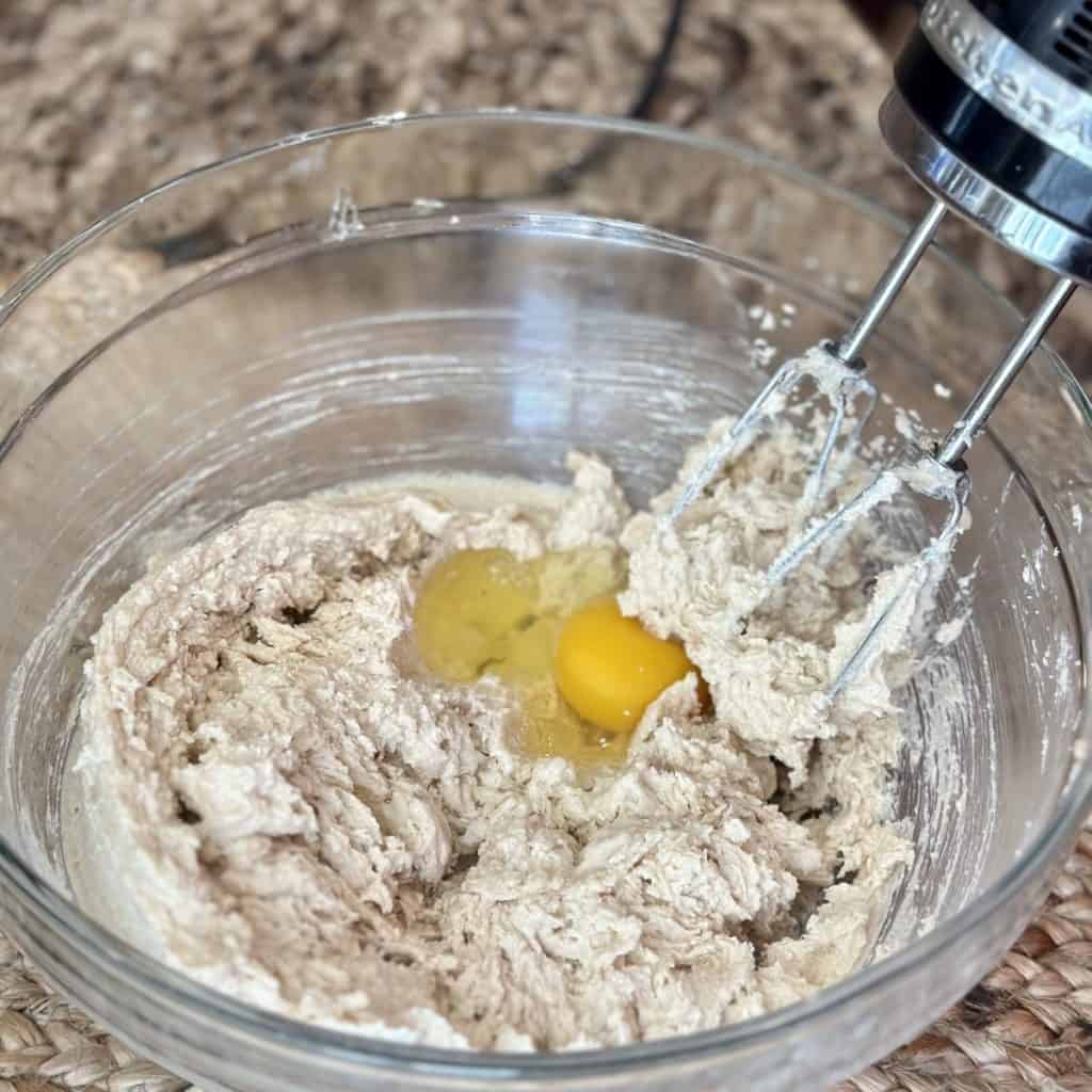 Adding eggs to butter and sugar in a bowl.