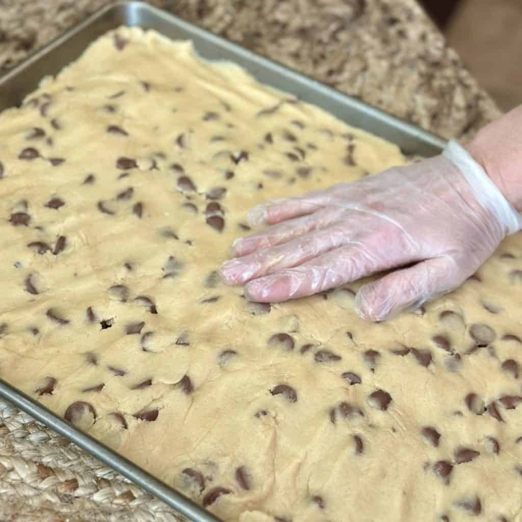 Pressing cookie dough batter in a sheet pan.