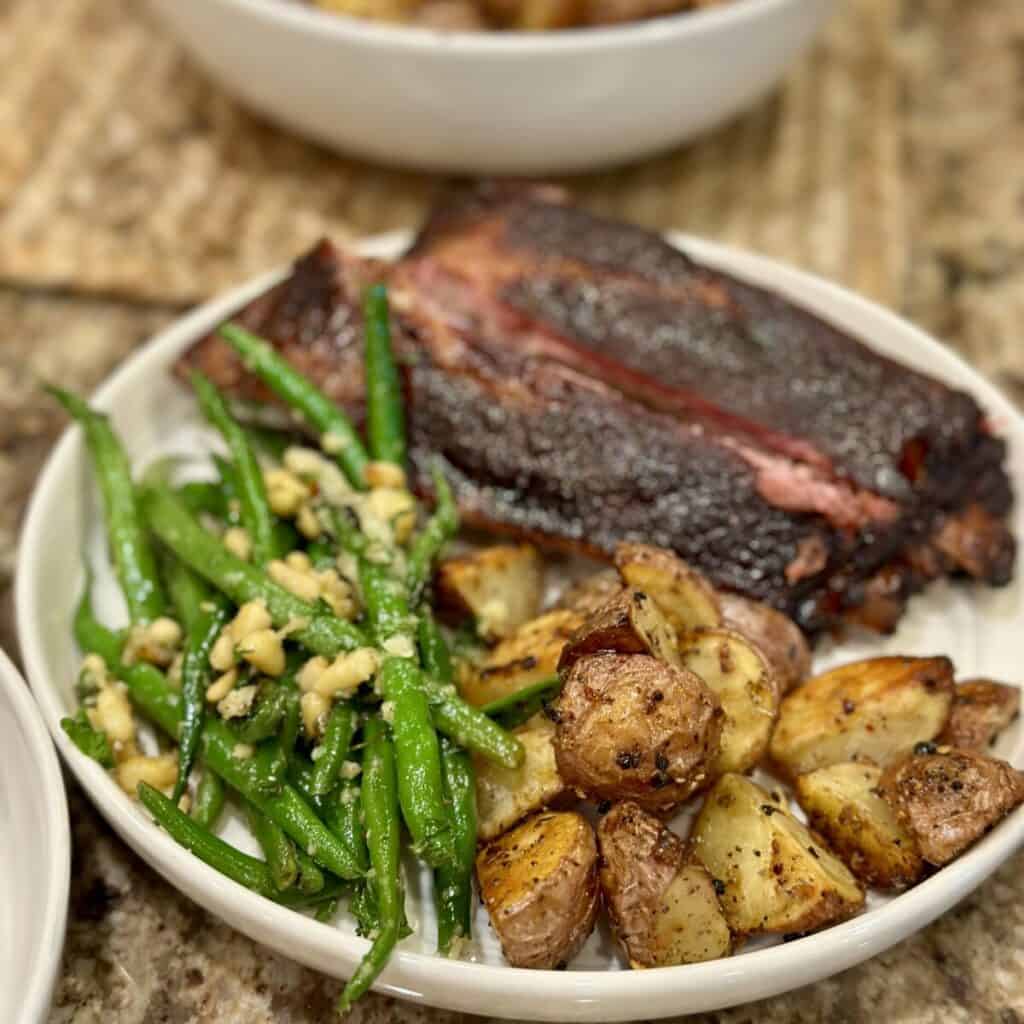 A plate with ribs, green beans and potatoes.