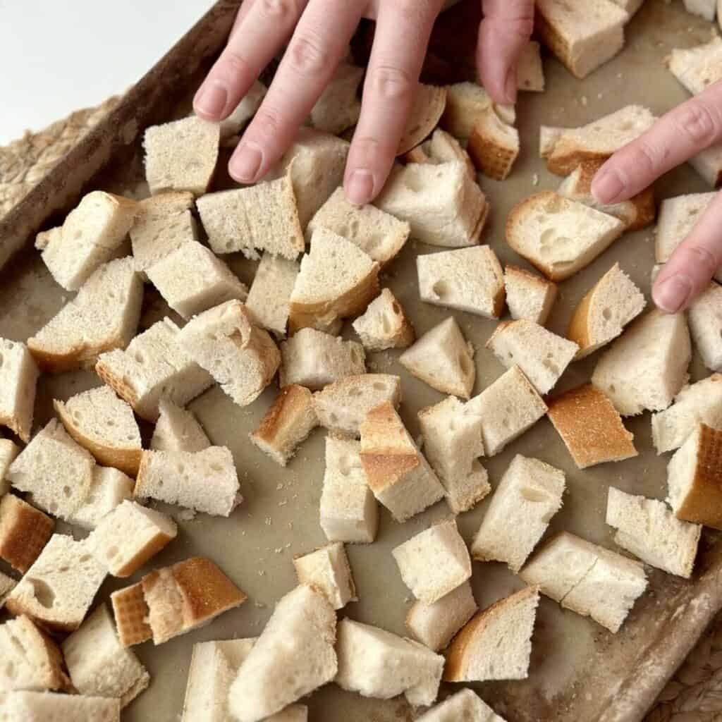 Spreading bread cubes on a sheet pan.