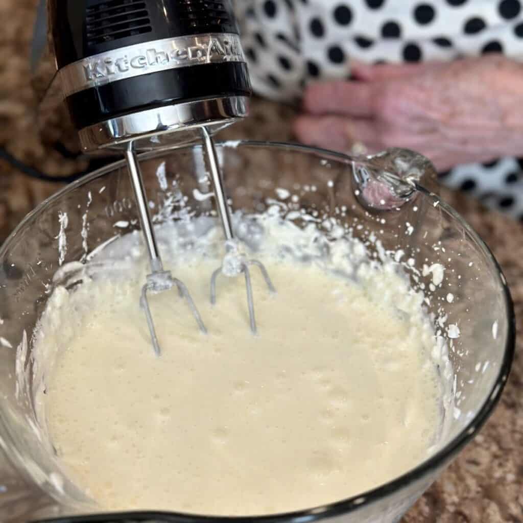 Whipping together lemon jello, cream cheese and cool whip.