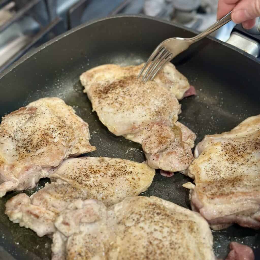 Searing chicken in a skillet.