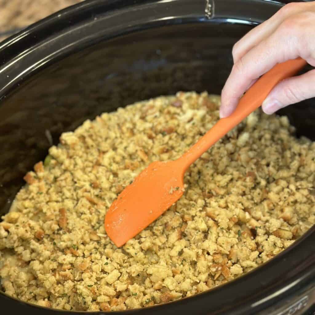 Adding stuffing to the top of gravy in a crockpot.