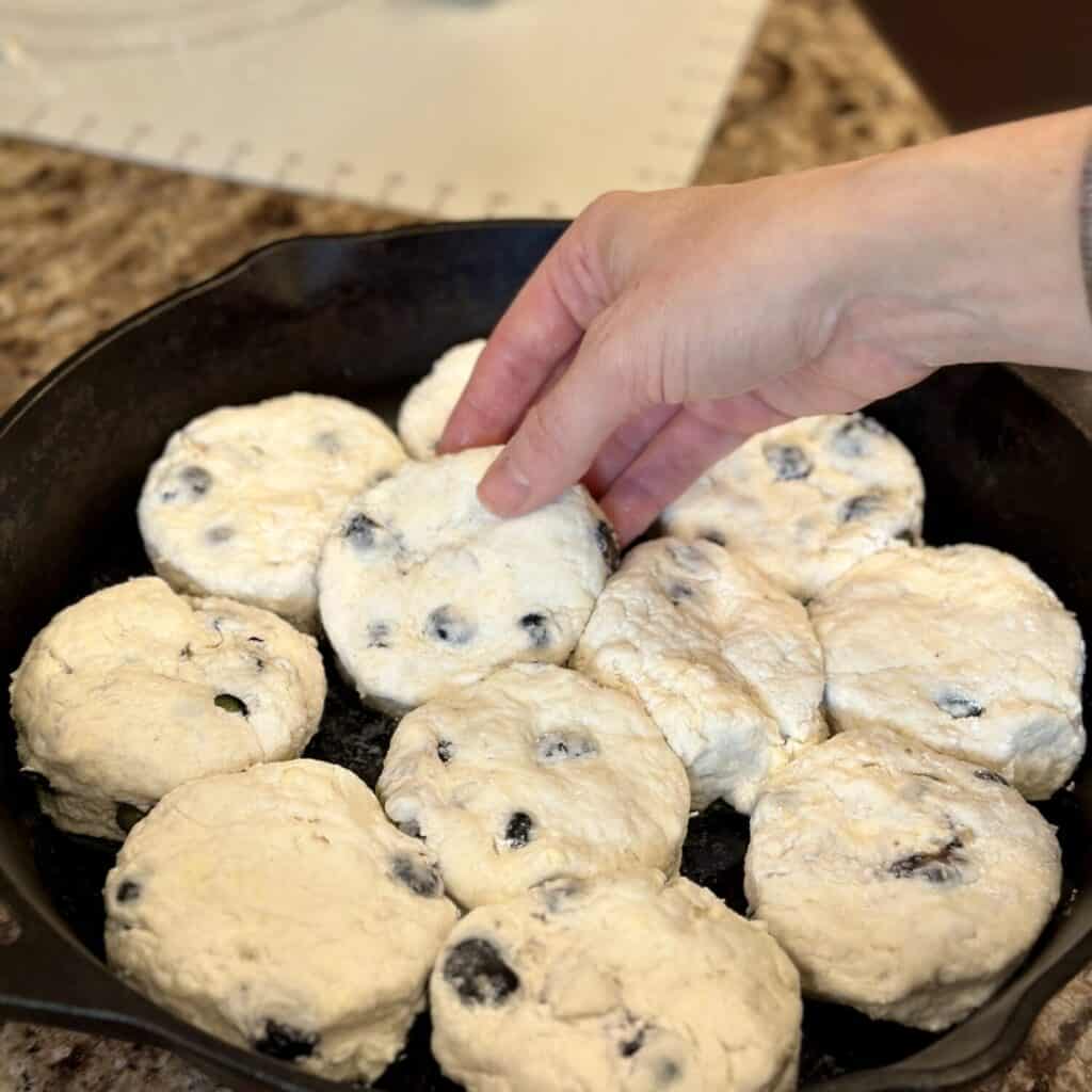 Laying biscuits in a cast iron skillet.