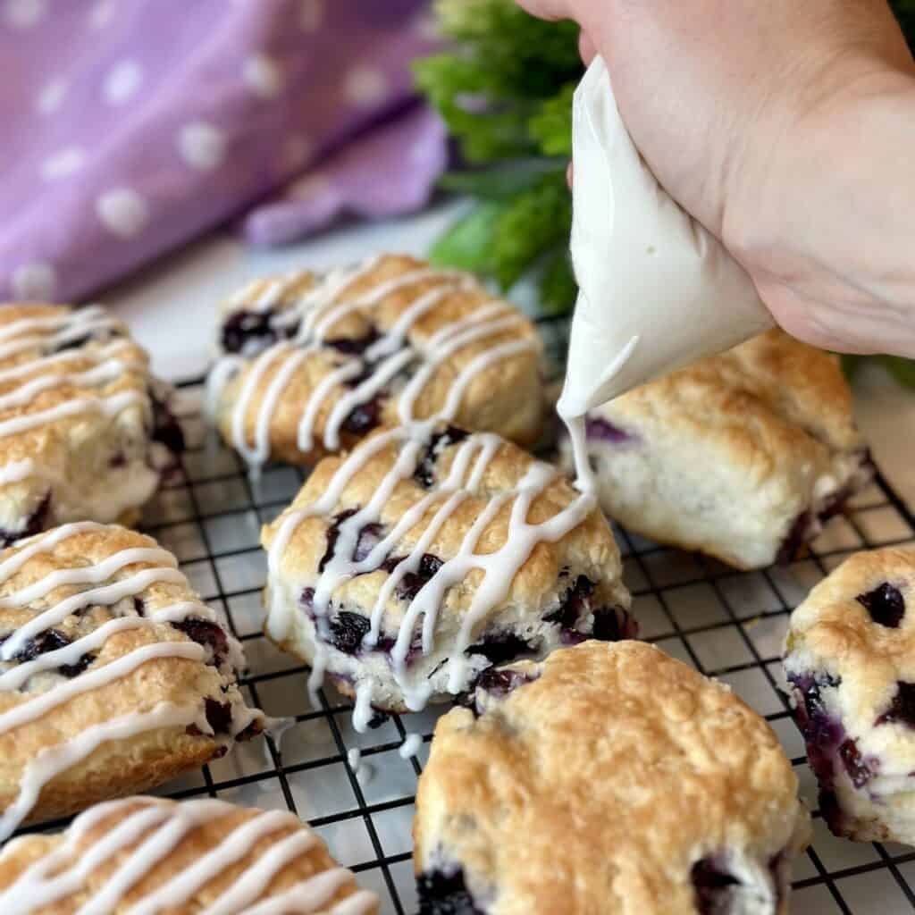 Drizzling icing on blueberry biscuits.