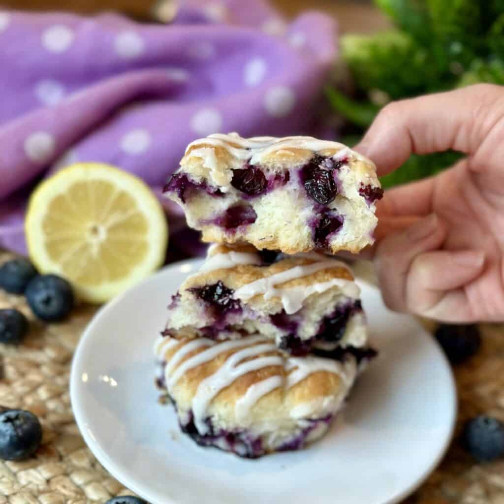 Holding a halved blueberry biscuit.