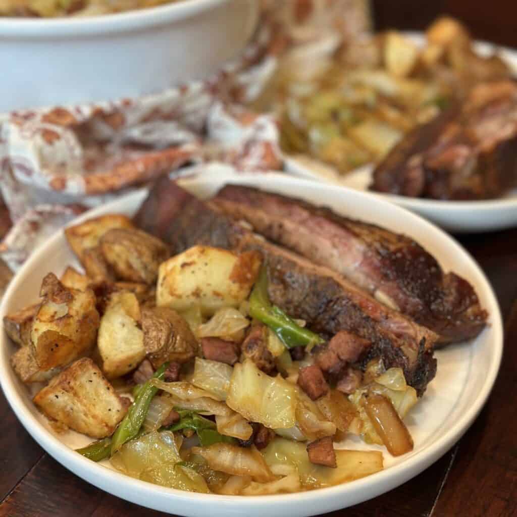 A plate of ribs, potatoes, and ham and cabbage.