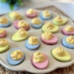 A plate of colored deviled eggs that are pink, green and blue.