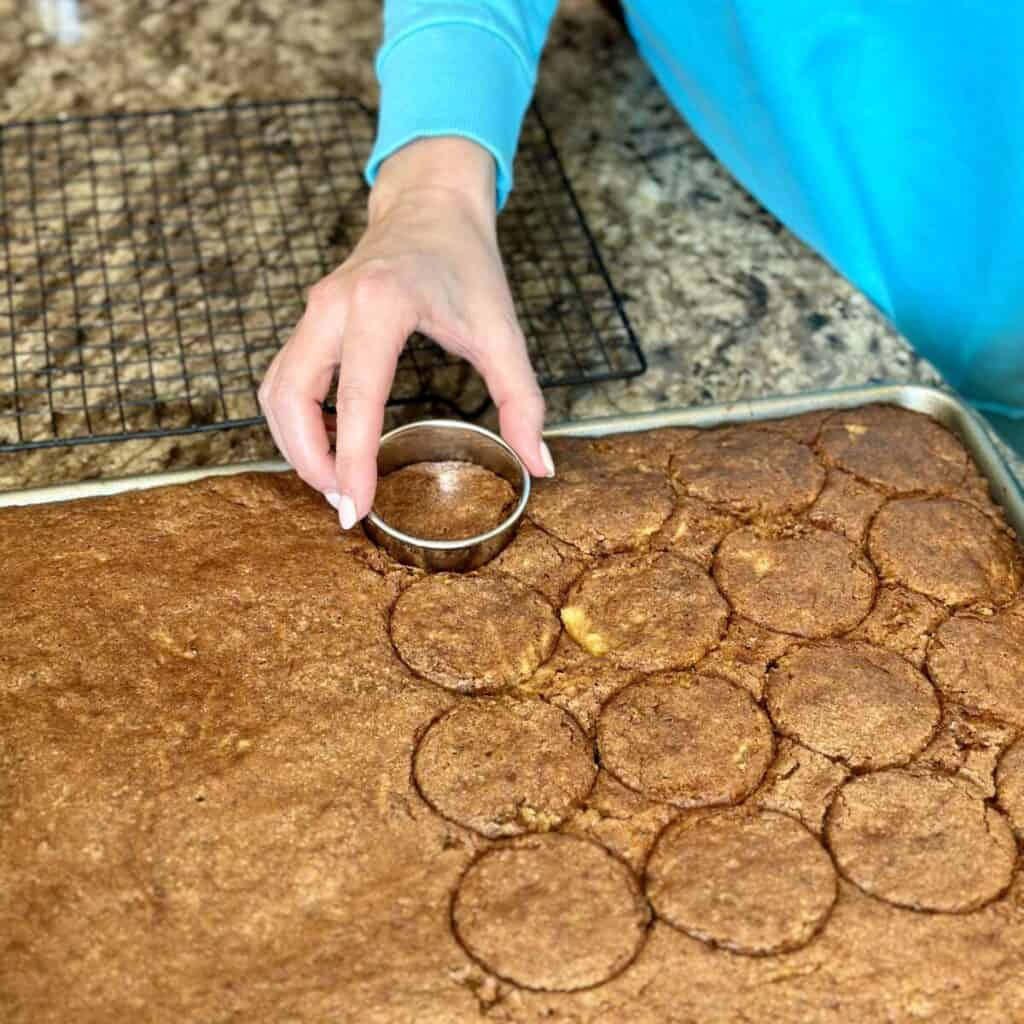 Cutting out mini carrot cakes from a sheet pan.