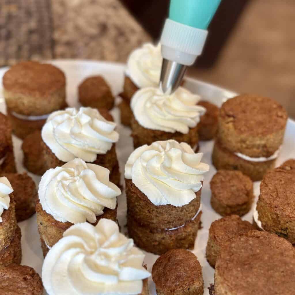 Adding icing to mini carrot cakes.