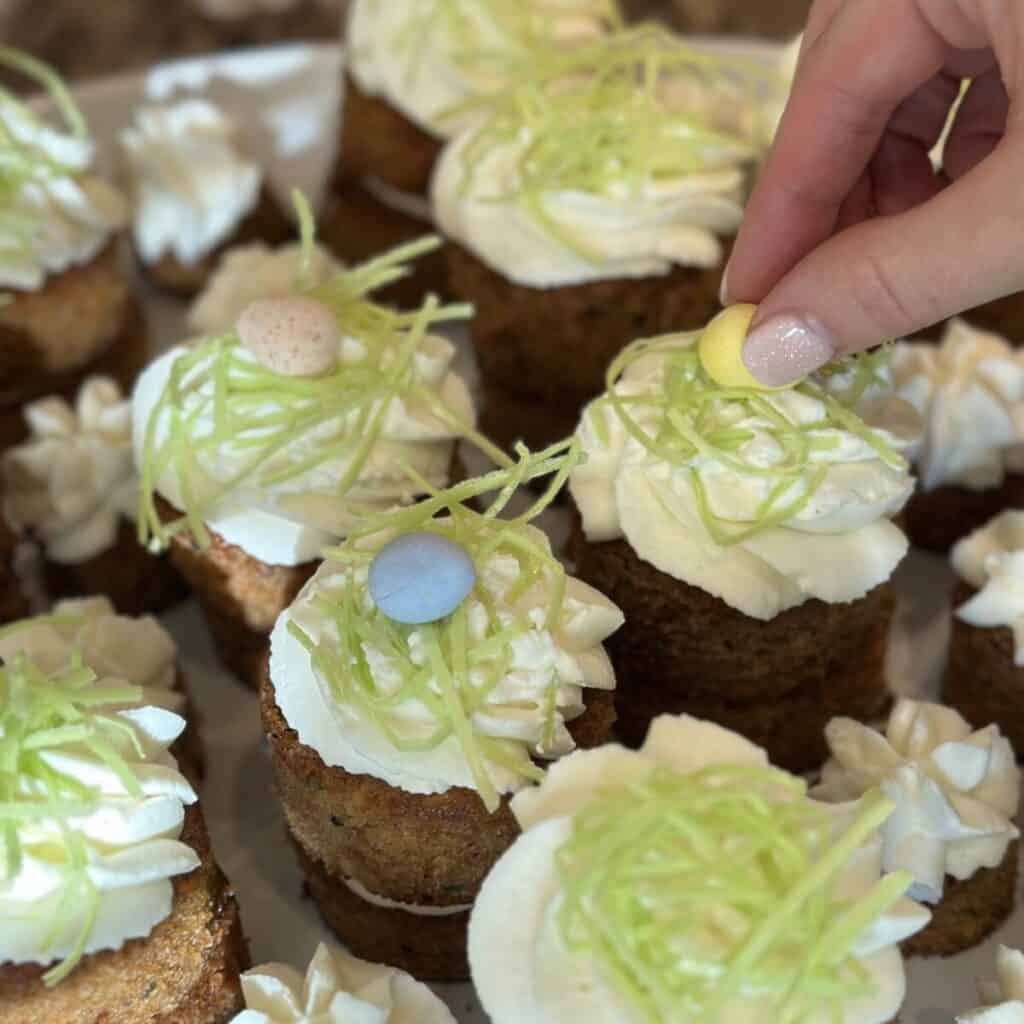 Decorating mini carrot cakes with Cadbury eggs and edible grass.