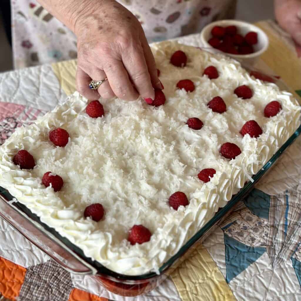 Placing raspberries on a zinger cake.