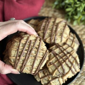 Holding an oatmeal cookie with chocolate and peanut butter on top.