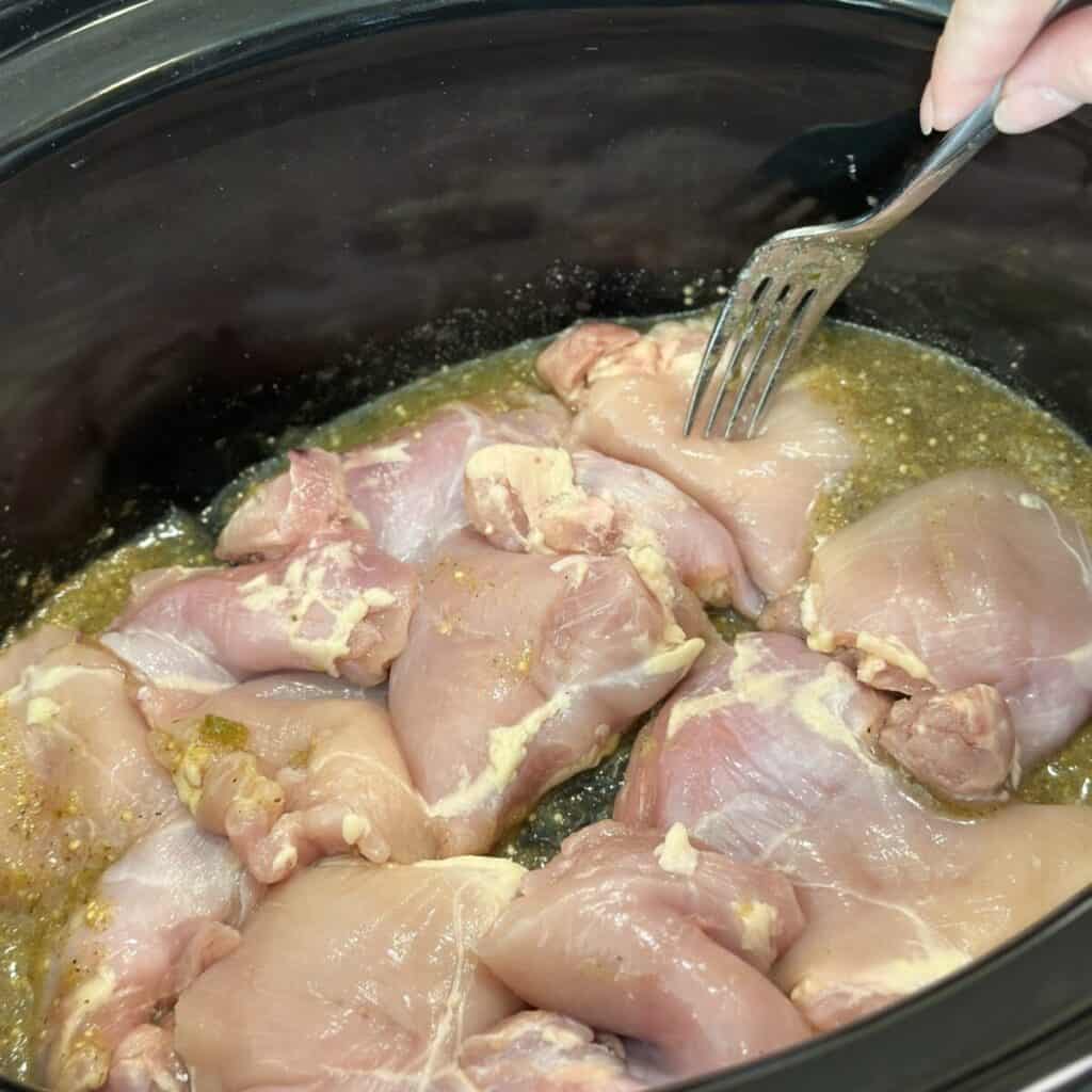 Adding chicken to a crockpot.