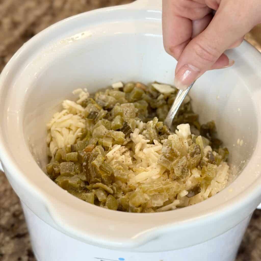 Mixing together the ingredients for white queso dip in a crockpot.