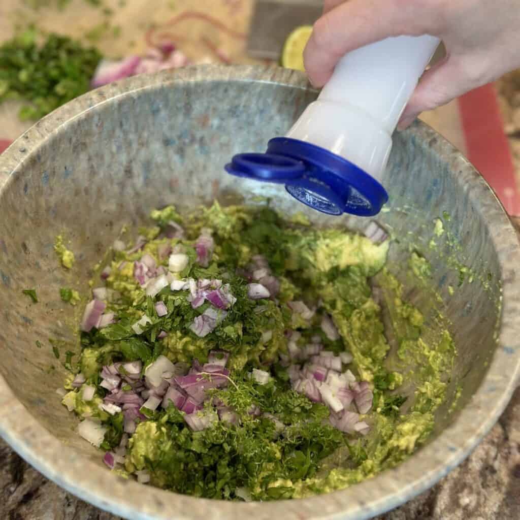 Adding salt to guacamole.