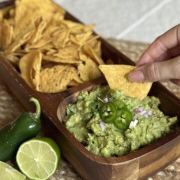 A bowl of guacamole with chips.