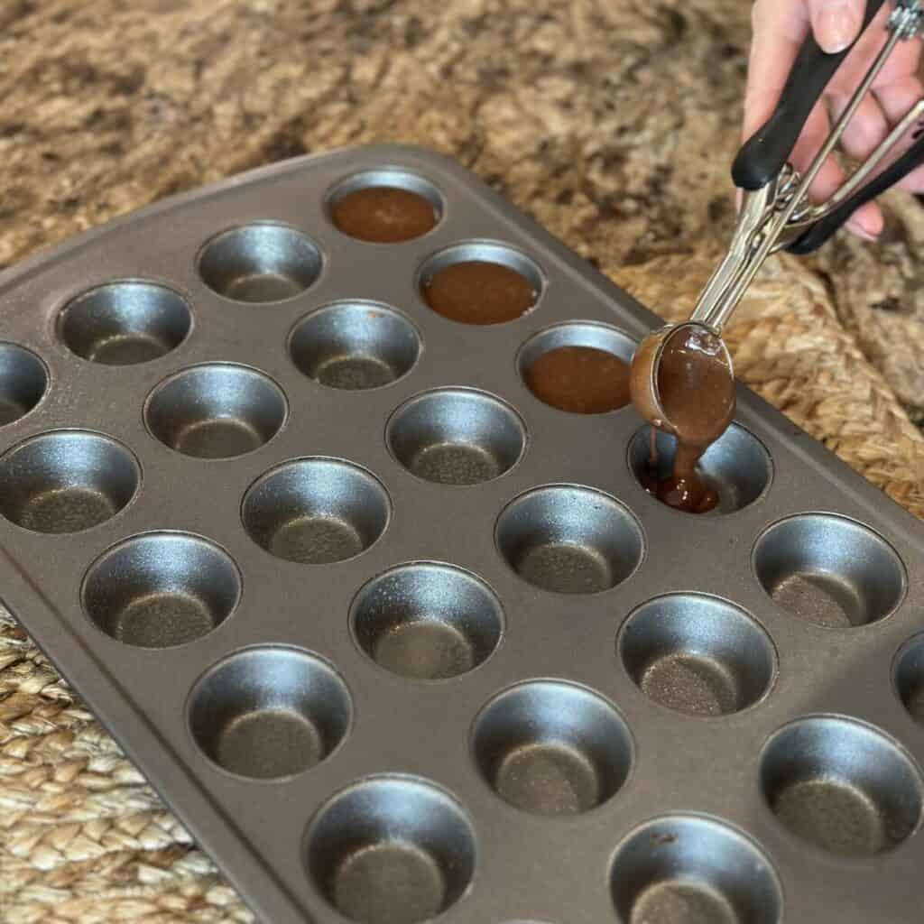 Scooping batter into a mini muffin pan.