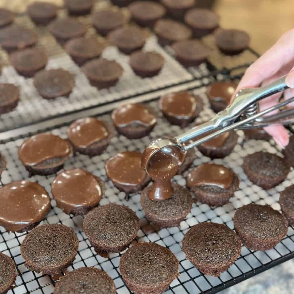 Scooping icing onto texas sheet cake bites.