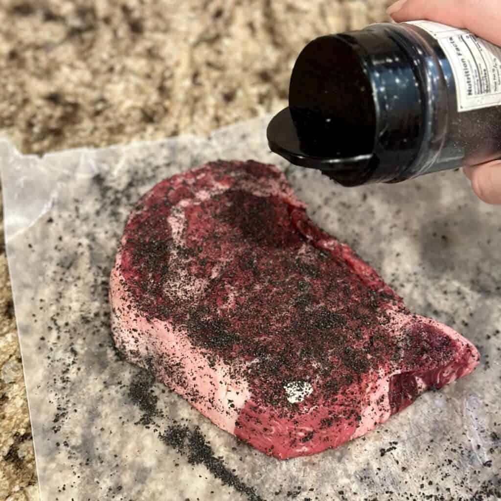 Seasoning a ribeye steak.
