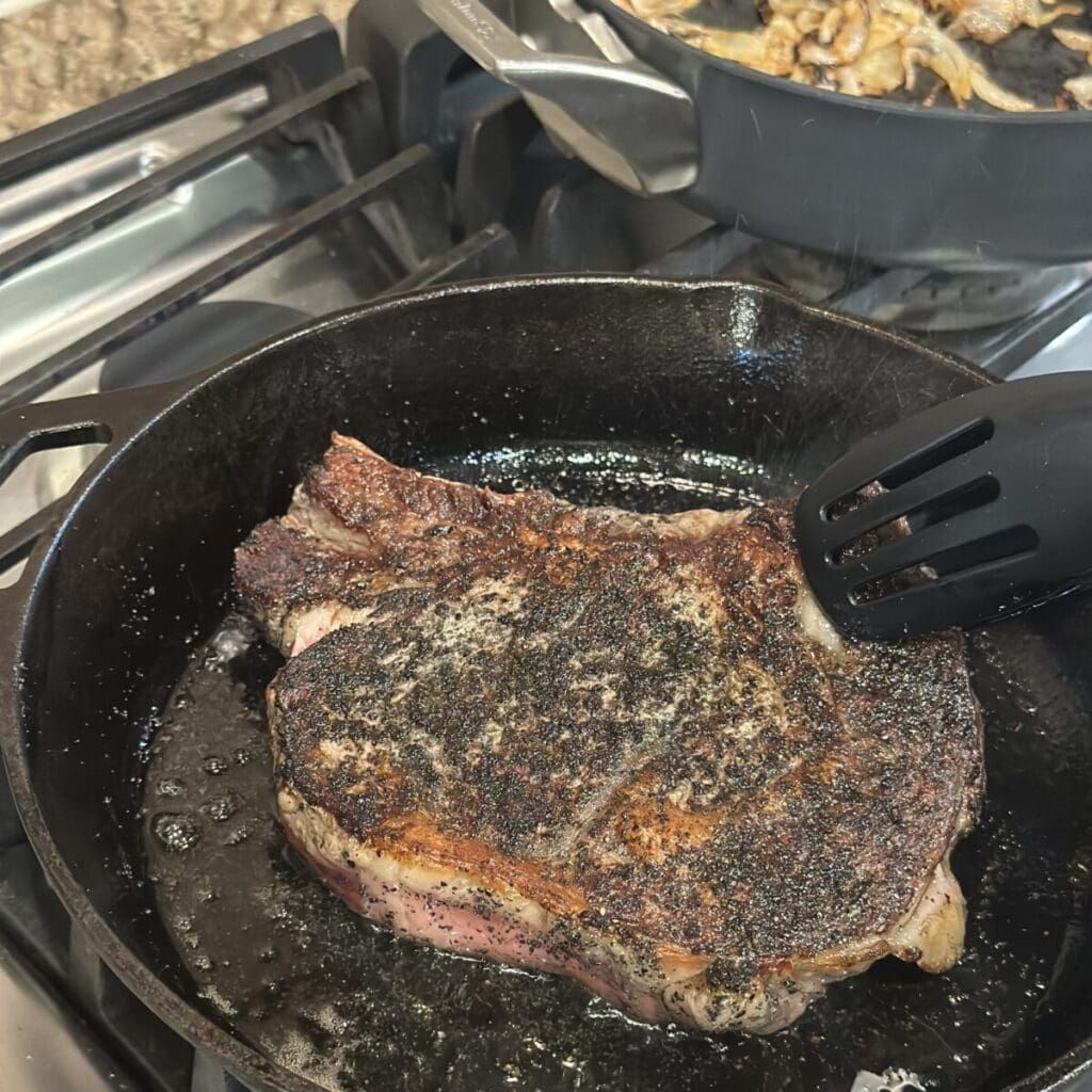 Searing a ribeye in a cast iron skillet.