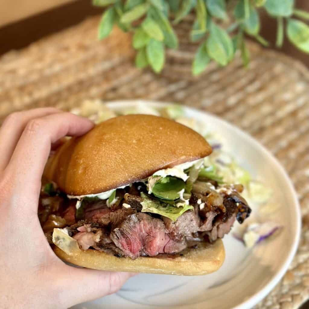 Holding a dressed ribeye sandwich.